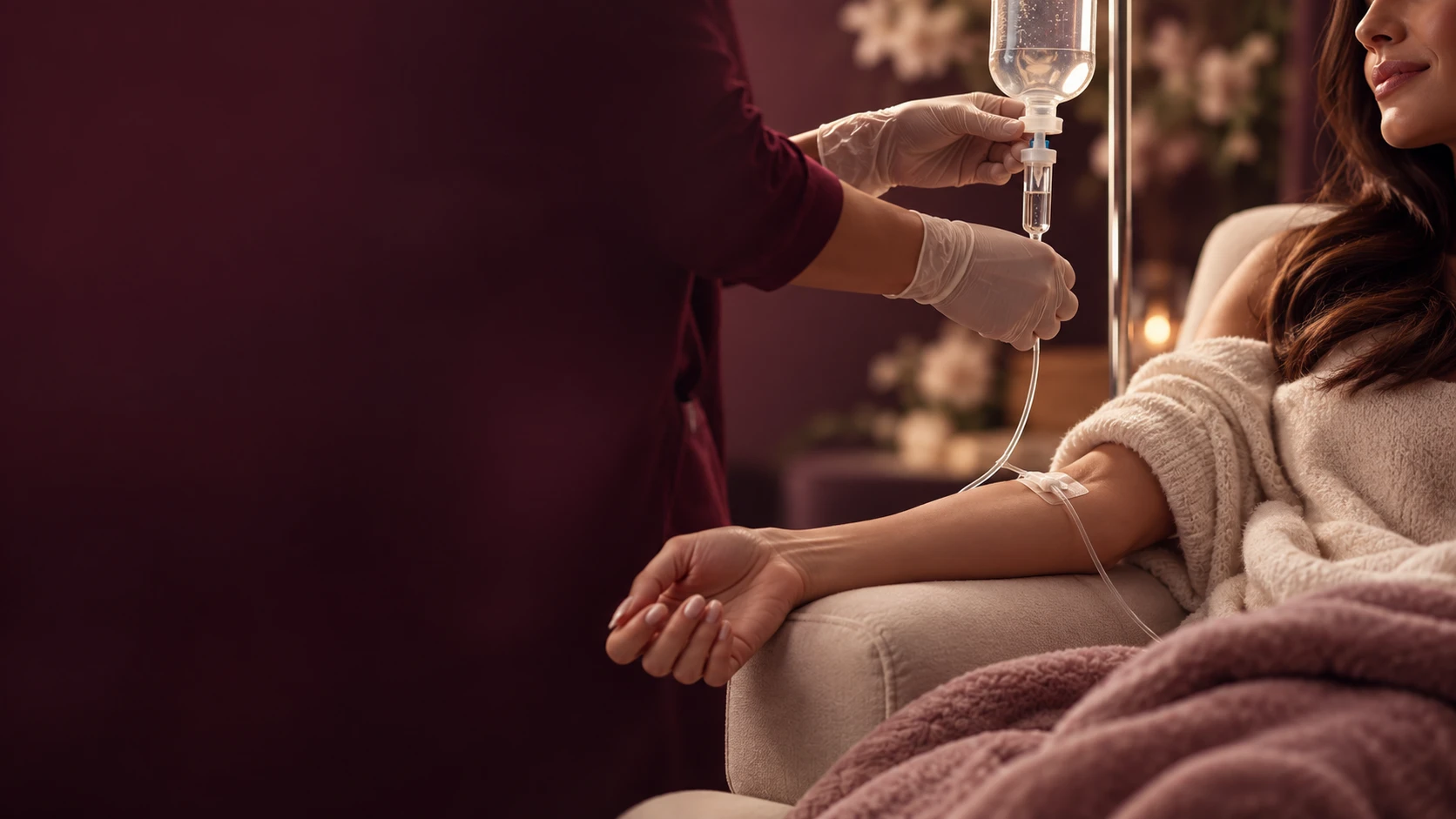 Woman resting under a blanket in a reclining chair while a provider adjusts her IV line