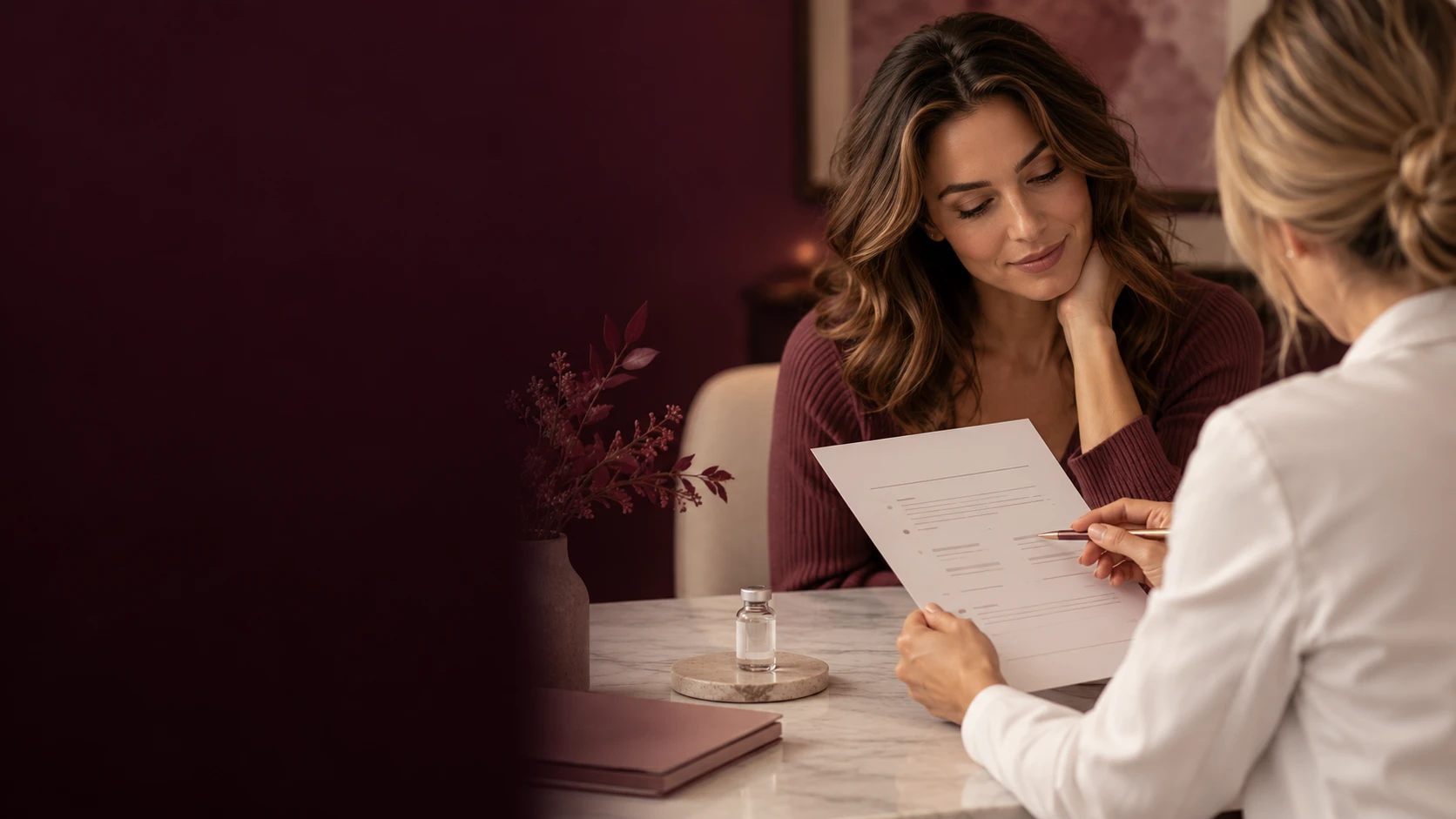Provider reviewing a written plan with a woman across a marble table, a small vial beside them