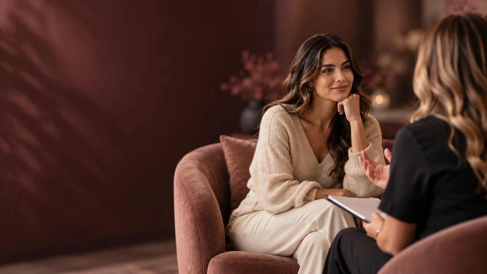 Two women talking during a consultation in blush armchairs