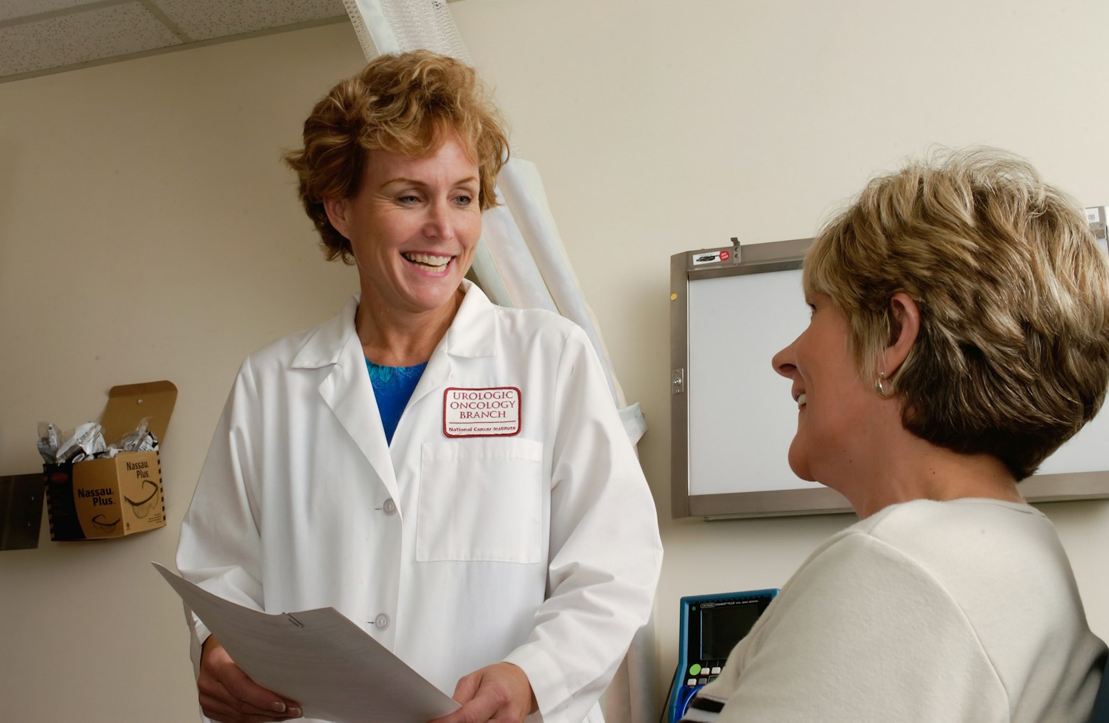 Smiling provider in a white coat reviewing notes with a patient