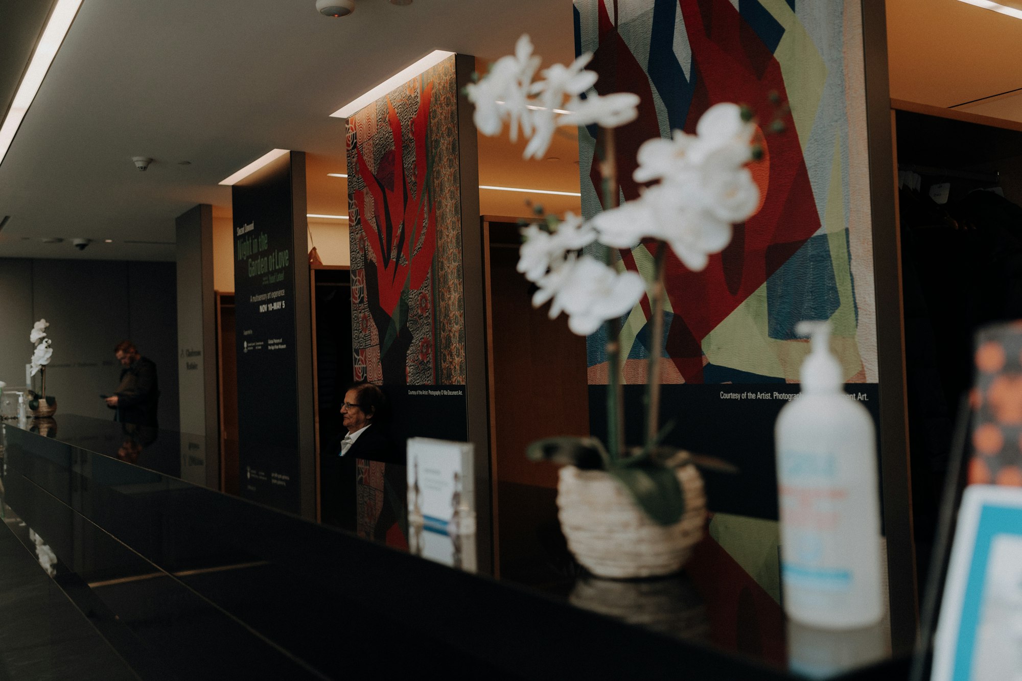 White orchids and skincare bottles on a dark counter in warm light